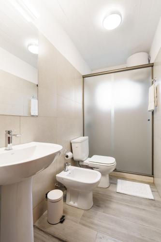 a white bathroom with a sink and a toilet at Taurinas in Colonia del Sacramento