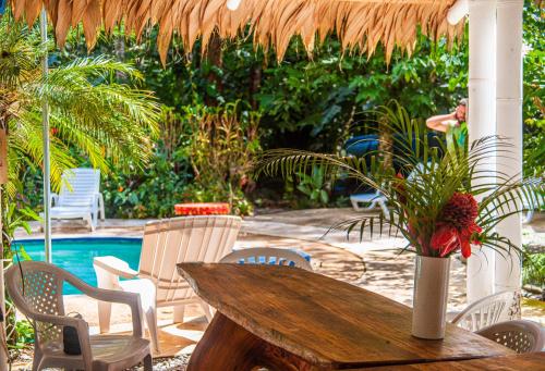 a wooden table and chairs and a table and a pool at Bambutel Cocles in Puerto Viejo