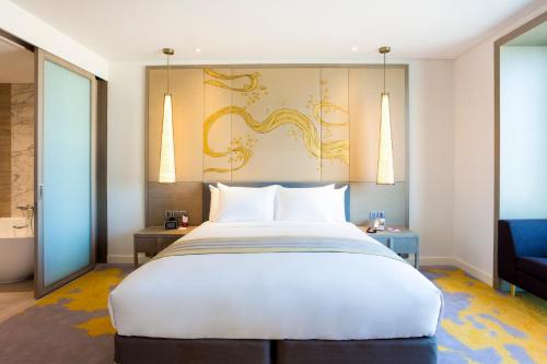 a bedroom with a large white bed and a blue chair at Crowne Plaza Vientiane, an IHG Hotel in Vientiane