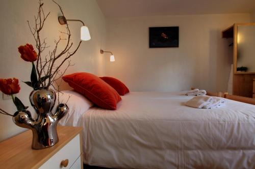 a bedroom with a bed with red pillows and a vase with roses at Les Campanules in Les Houches
