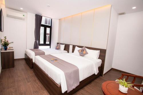a bedroom with two beds with white sheets at Nile Hotel Phu Yen in Tuy Hoa