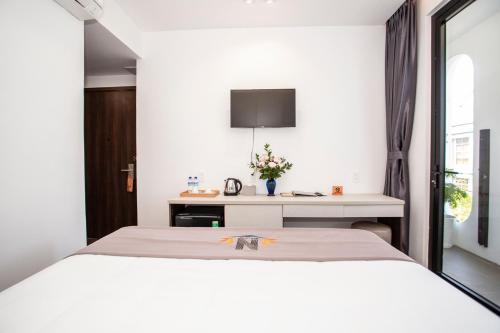 a bedroom with a white bed and a desk at Nile Hotel Phu Yen in Tuy Hoa