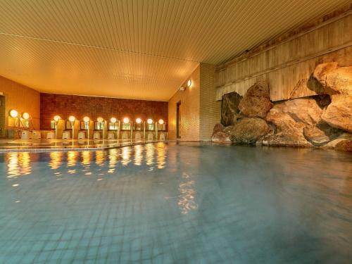 a swimming pool in a hotel with a rock wall at Yukai Resort Hana-Saichoraku in Kaga