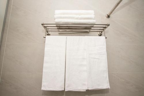 a towel rack with white towels on it in a bathroom at Nile Hotel Phu Yen in Tuy Hoa