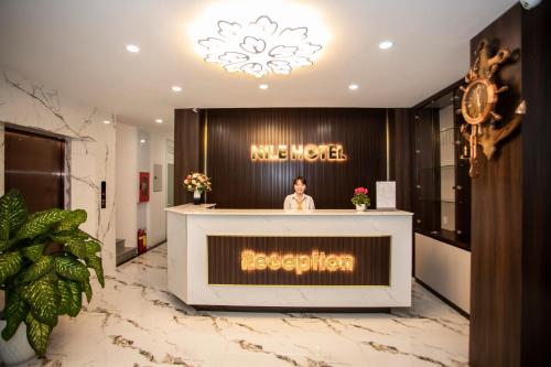a woman standing at a reception desk in a lobby at Nile Hotel Phu Yen in Tuy Hoa
