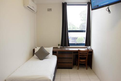 a room with two beds and a desk and a window at Wiley Park Hotel in Sydney