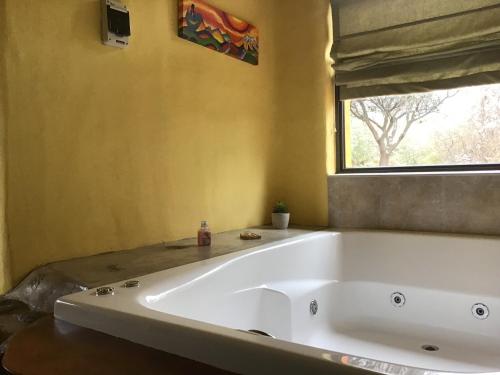 baño con una gran bañera blanca y ventana en Cabañas Chacras del Arroyo Vidal en Carpintería