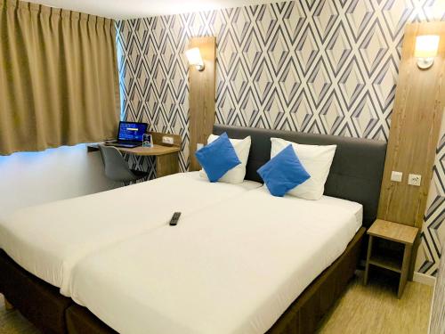 a bedroom with a large bed with blue pillows at Hotel RBX - Roubaix Centre in Roubaix