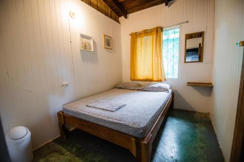 a small bed in a room with a window at Pura Vida Mini Hostel Santa Teresa in Santa Teresa Beach