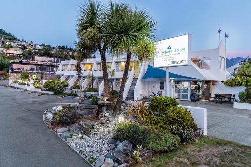 a building with palm trees in a parking lot at Amity Serviced Apartments in Queenstown