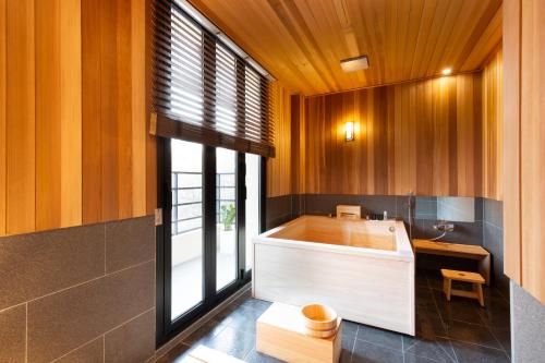uma banheira na casa de banho com paredes de madeira em Tomonoya Hotel and Ryokan Gyeongju em Gyeongju
