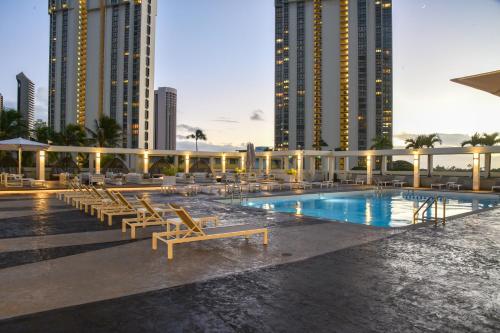 a swimming pool with lounge chairs and tall buildings at Ala Moana Honolulu by Mantra in Honolulu