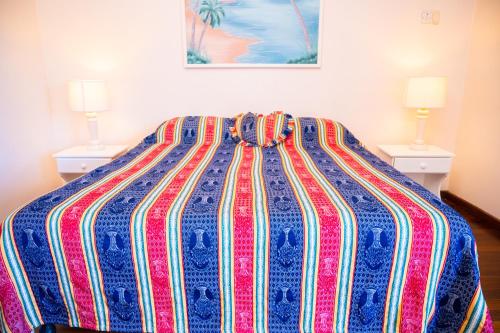 a bed with a colorful blanket on it with two lamps at Shields Negril Villas in Negril