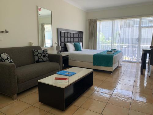a bedroom with a bed and a couch and a table at Tweed Central Motel in Tweed Heads