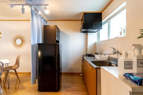 a kitchen with a black refrigerator and a sink at Type C Room 40平米 -ウル エスポワール那覇- in Kume