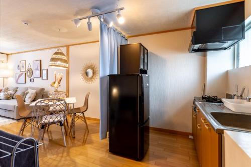 a kitchen and living room with a black refrigerator at Type C Room 40平米 -ウル エスポワール那覇- in Kume