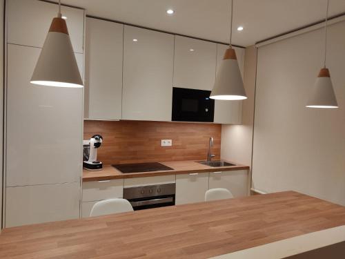 a kitchen with white cabinets and a table with chairs at Apartamento Costa II con Parking exterior comunitario in Zumaia