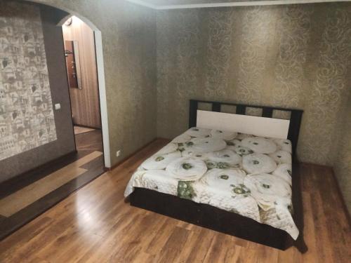 1 dormitorio con 1 cama con sábanas blancas y suelo de madera en Always at home Apartment OnTransportnaya 11, en Novokuznetsk