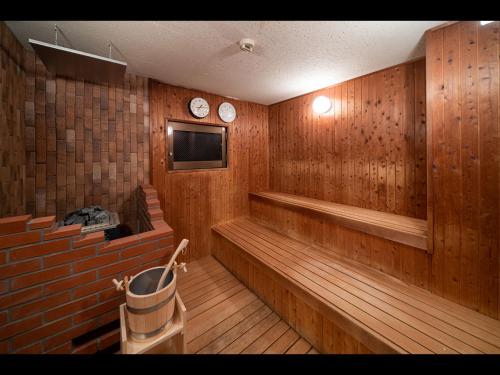 a wooden room with a tub and two clocks on the wall at Capsule Plus Yokohama Sauna & Capsule in Yokohama