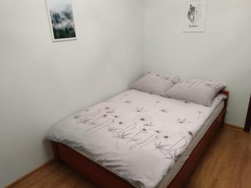 uma pequena cama num quarto com paredes brancas em Apartament MAZURIA2 em Ełk