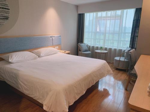 Un dormitorio con una gran cama blanca y una ventana en Home Inn Mianyang People'S Park, en Mianyang