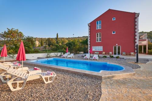 una piscina con sillas y sombrillas junto a un edificio en Villa Liberty, en Cavtat