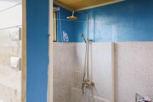 a shower in a bathroom with a blue wall at 山板樵愛面子民宿 in Sanyi
