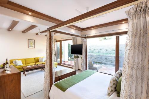 a bedroom with a bed and a living room at Suryavilas Luxury Resort & Spa in Kasauli