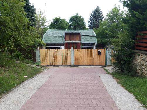 a house with a wooden gate and a brick driveway at Attila's Guest House in Budaörs