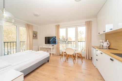 a bedroom with a bed and a kitchen with a table at Aura Sopot Studio Apartments in Sopot