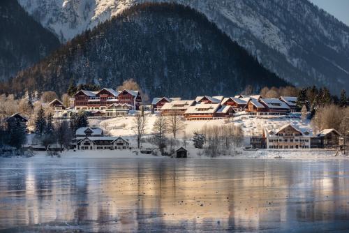 a village in the snow next to a body of water at MONDI Hotel am Grundlsee in Grundlsee