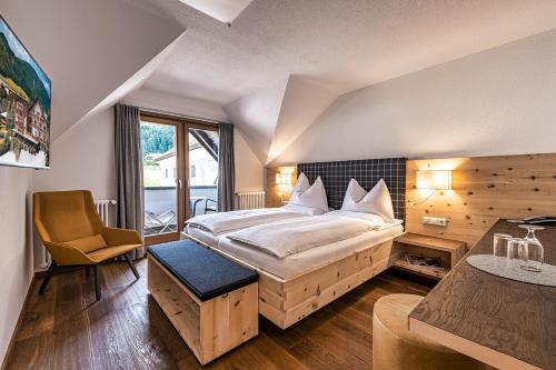 ein Schlafzimmer mit einem großen Bett und einem Schreibtisch in der Unterkunft Hotel Brötz in Rasùn di Sotto