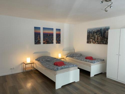 two beds in a room with two lamps and paintings at Kleine Wohnung im Herzen von Leverkusen Opladen in Leverkusen