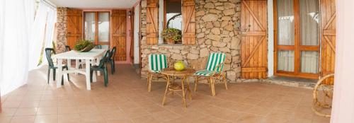 Habitación con mesa, sillas y pared de piedra. en Villa Bados 6 - Klodge en Olbia