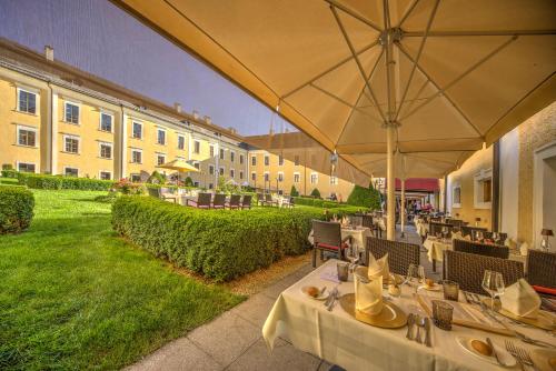 a restaurant with tables and umbrellas next to a building at Schlosshotel Mondsee in Mondsee