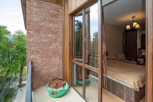 a bedroom with a bed and a balcony with a window at Park Residence Forest View in Bakuriani
