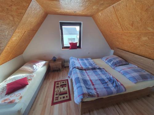 an attic bedroom with two beds and a window at Agroturystyka Dobri mól in Kiedrowice