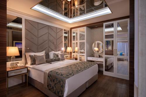 a bedroom with a large white bed and a mirror at Elysium Green Suites in Antalya