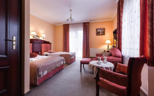 um quarto de hotel com duas camas e um sofá em Hotel Adam & Spa em Kudowa-Zdrój