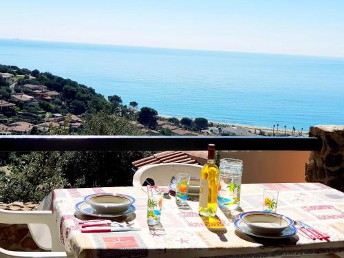 a table with plates and a bottle of wine on a balcony at Villino Mari Pintau Best Vacation Ever in Geremèas