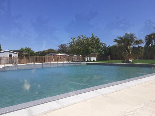 une grande piscine avec de l'eau bleue dans une cour dans l'établissement MOBILHOME agréable sans draps ni serviettes, à Port-la-Nouvelle