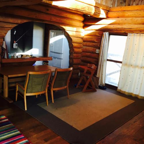 comedor en una cabaña de madera con mesa y sillas en NaGano-log house en Chino