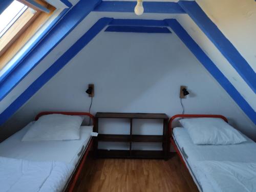 twee bedden in een kamer met twee ramen bij Petite maison du manoir de Keryvoas in Kerlouan