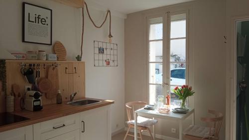 cocina con fregadero, mesa y ventana en T2 D en coeur de Balaruc dans maison avec jardin ideal couple de curistes en Balaruc-les-Bains