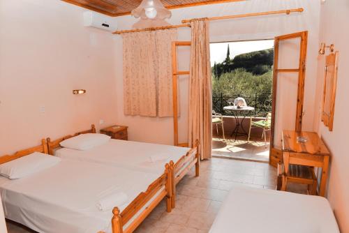 a bedroom with two beds and a balcony with a table at Paradise Studios in Paleokastritsa