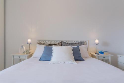 a bedroom with a white bed with blue and white pillows at Lido di Spina vista mare pineta - A Casa di Alessandra in Lido di Spina