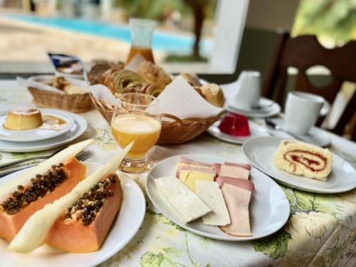 una mesa con platos de comida, bebida y pan en Pousada Della Vegas, en Serra Negra
