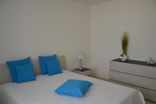 ein Schlafzimmer mit einem großen Bett mit blauen Kissen in der Unterkunft Il Crepuscolo Apartment - Villaggio di Mary in Locorotondo