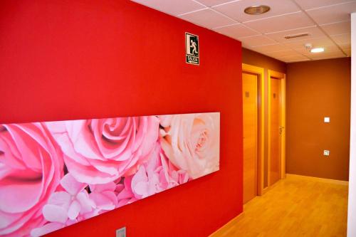 a red wall with a painting of roses on it at Hotel El Cruce Moraleda in Moraleda de Zafayona