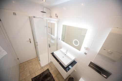 a white bathroom with a sink and a shower at Rhön Häuschen in Bischofsheim an der Rhön